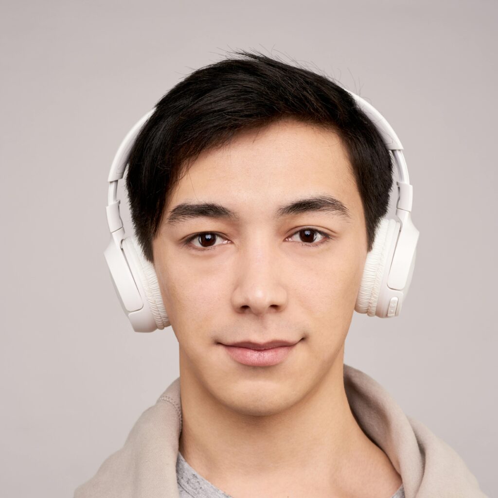 Portrait of a young man wearing wireless headphones, enjoying music.