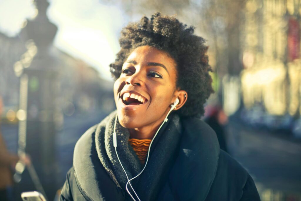 Smiling young woman enjoying music in urban Budapest setting. Vibrant and joyful moment.